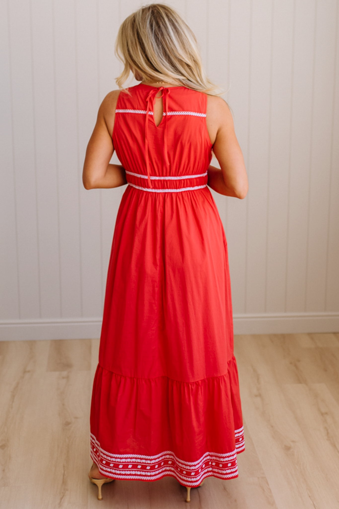 Woman wearing a red dress with white trim in a minimal indoor setting