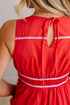 Red dress with white trim worn by a person, against a neutral background