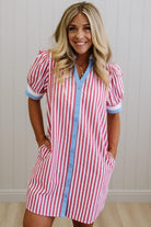 Woman wearing a red and white striped dress with blue trim against a neutral background
