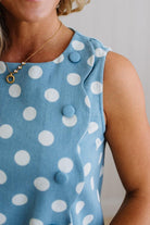 Blue dress with white polka dots worn by a person, with a neutral background