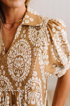 Close-up of a woman wearing a brown and white patterned blouse with puff sleeves and a smocked bodice.
