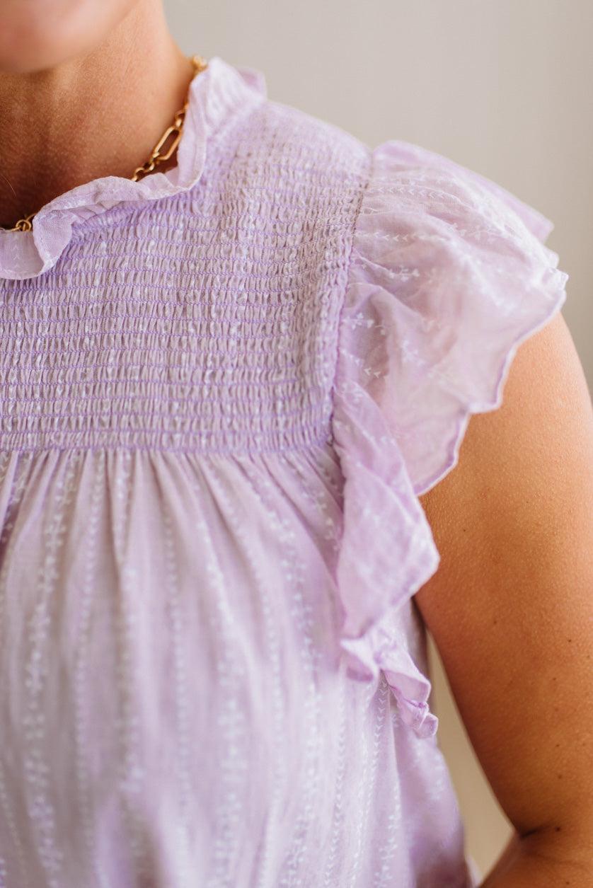 Close-up of a person wearing a light purple dress with ruffled sleeves.