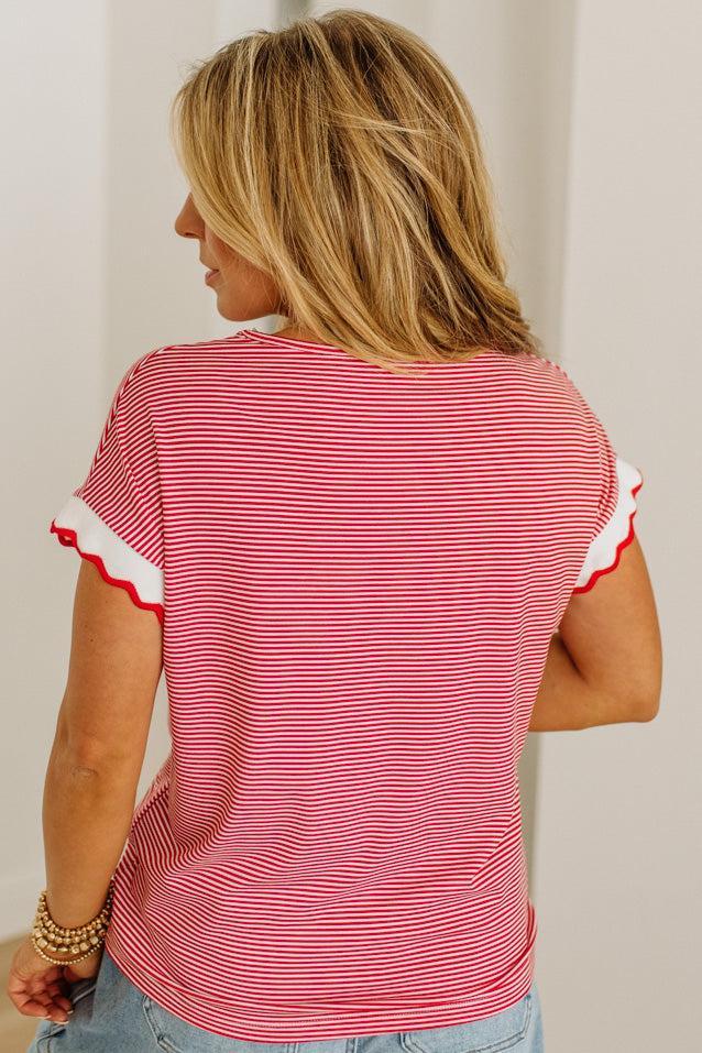 Woman wearing a red and white striped shirt with ruffled sleeves against a plain background