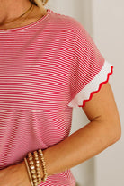 Red and white striped shirt with ruffled sleeves worn by a person.