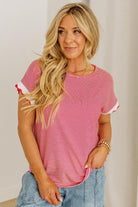 Woman wearing a red and white striped shirt with blue jeans against a plain background