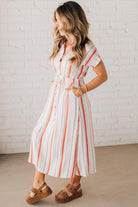 BLONDE WOMAN WEARING A RED AND WHITE DRESS WITH VERTICAL STRIPES, SIDE POCKETS, SHORT SLEEVE, BUTTON DOWN, FAUX TIE WAIST AND MIDI LENGTH.