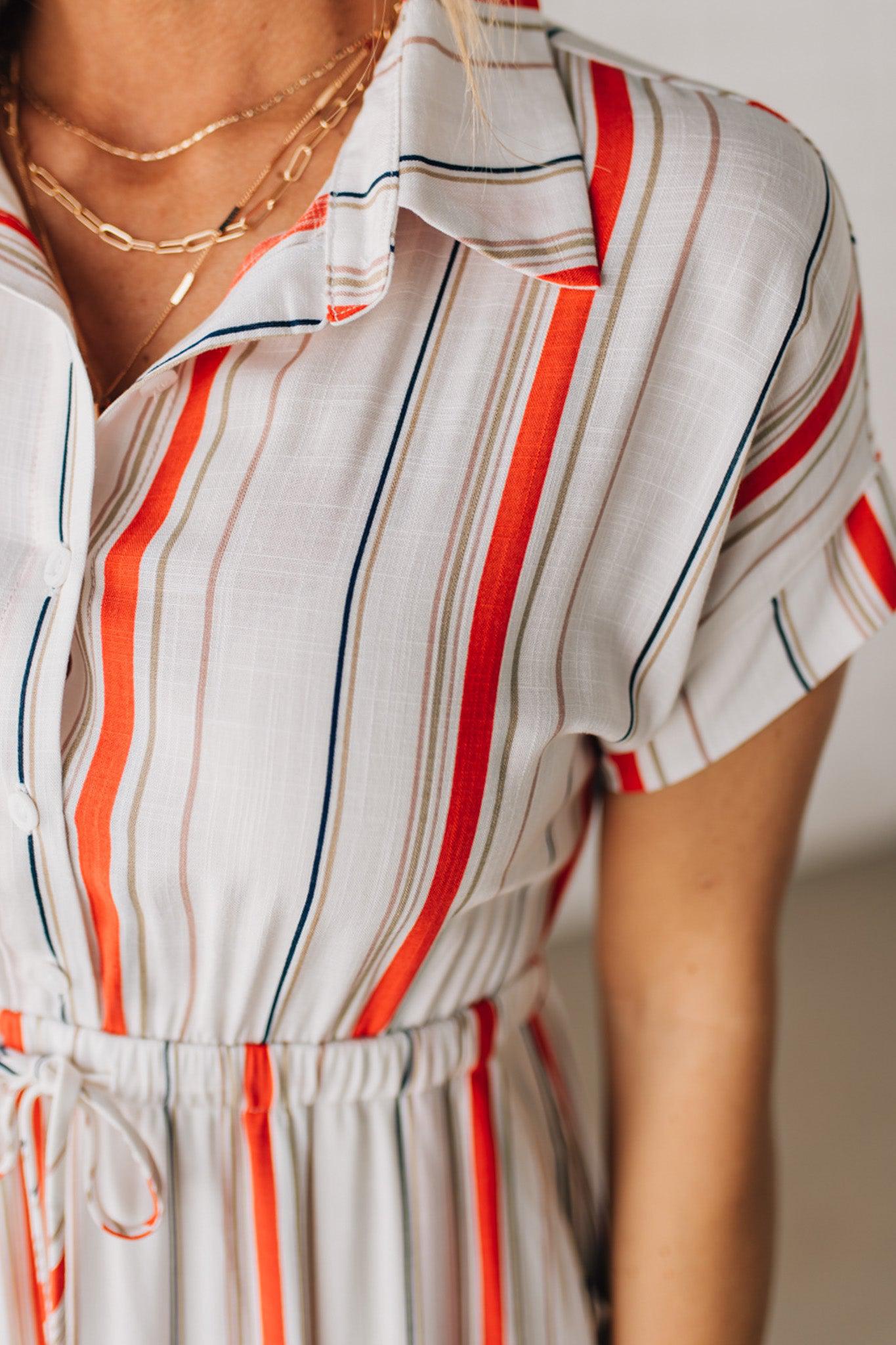 BLONDE WOMAN WEARING A RED AND WHITE DRESS WITH VERTICAL STRIPES, SIDE POCKETS, SHORT SLEEVE, BUTTON DOWN, FAUX TIE WAIST AND MIDI LENGTH.