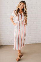 BLONDE WOMAN WEARING A RED AND WHITE DRESS WITH VERTICAL STRIPES, SIDE POCKETS, SHORT SLEEVE, BUTTON DOWN, FAUX TIE WAIST AND MIDI LENGTH.