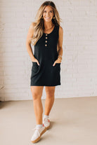 BLONDE WOMAN MODELING A RIBBED TANK DRESS WITH HENLEY STYLE WOOD BUTTONS AND TWO FRONT POCKETS