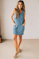 BLONDE WOMAN MODELING A RIBBED TANK DRESS WITH HENLEY STYLE WOOD BUTTONS AND TWO FRONT POCKETS