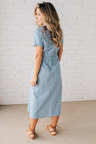 Blonde woman wearing a blue mid lenght dress with button front, double drawstring waist, and collar.