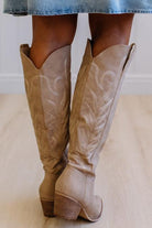 Tan knee-high boots with platform sole on a neutral background