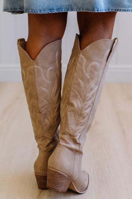 Tan knee-high boots with platform sole on a neutral background