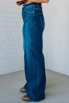 Person wearing blue jeans against a white brick wall.