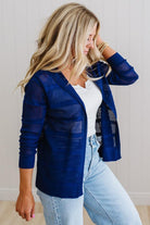 Woman wearing a blue cardigan over a white top and light blue jeans.
