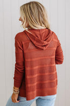 Person wearing a rust-colored ribbed hoodie against a white background