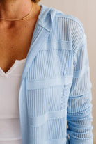 Light blue textured cardigan worn over a white top against a neutral background