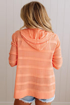 Person wearing a peach-colored hooded cardigan against a neutral background