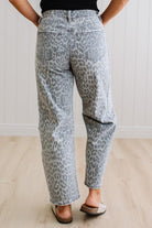 Person wearing gray leopard print pants on a plain background