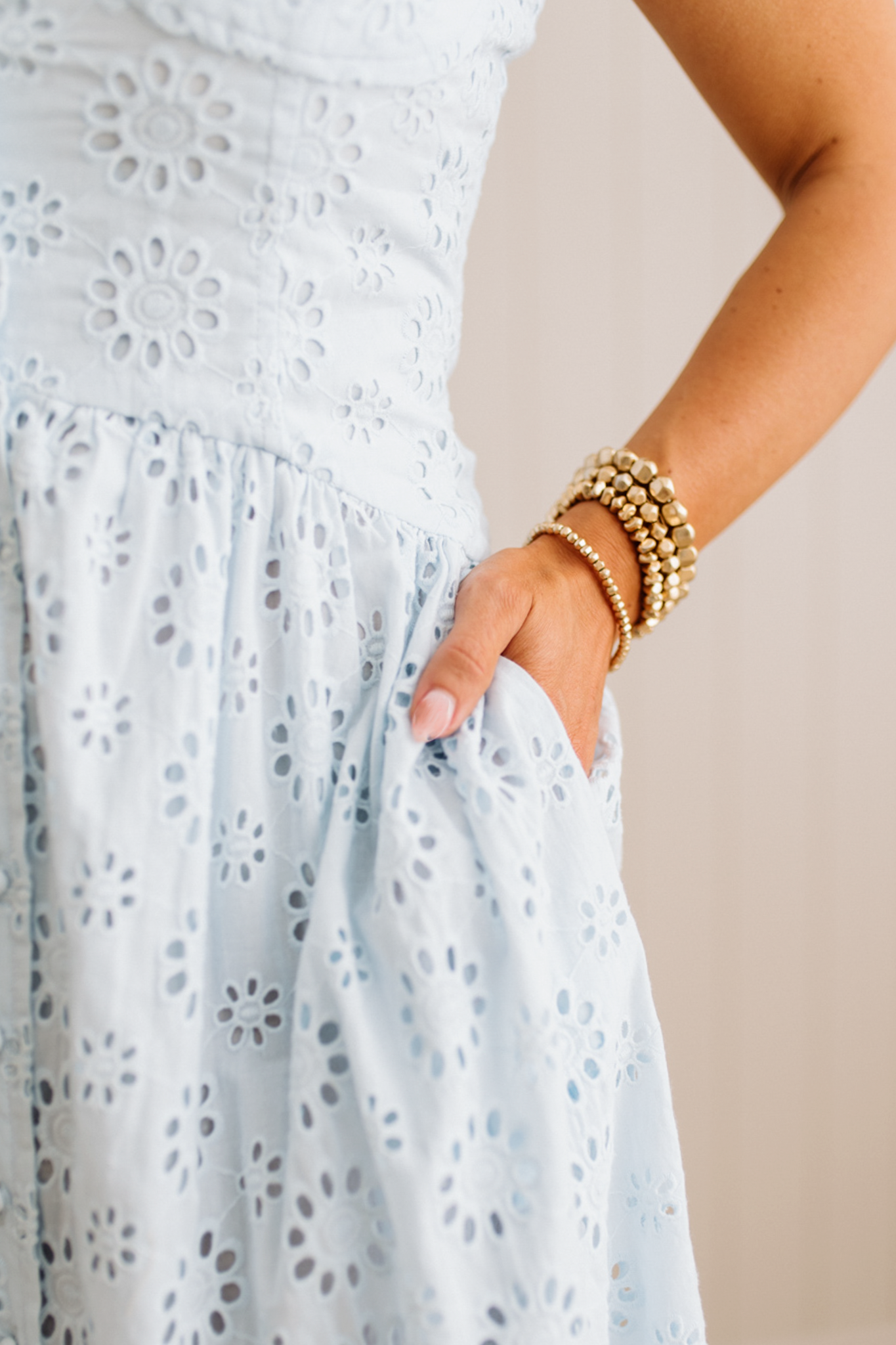 Blonde Woman wearing an eyelet lace dress with button front and spaghetti strap.