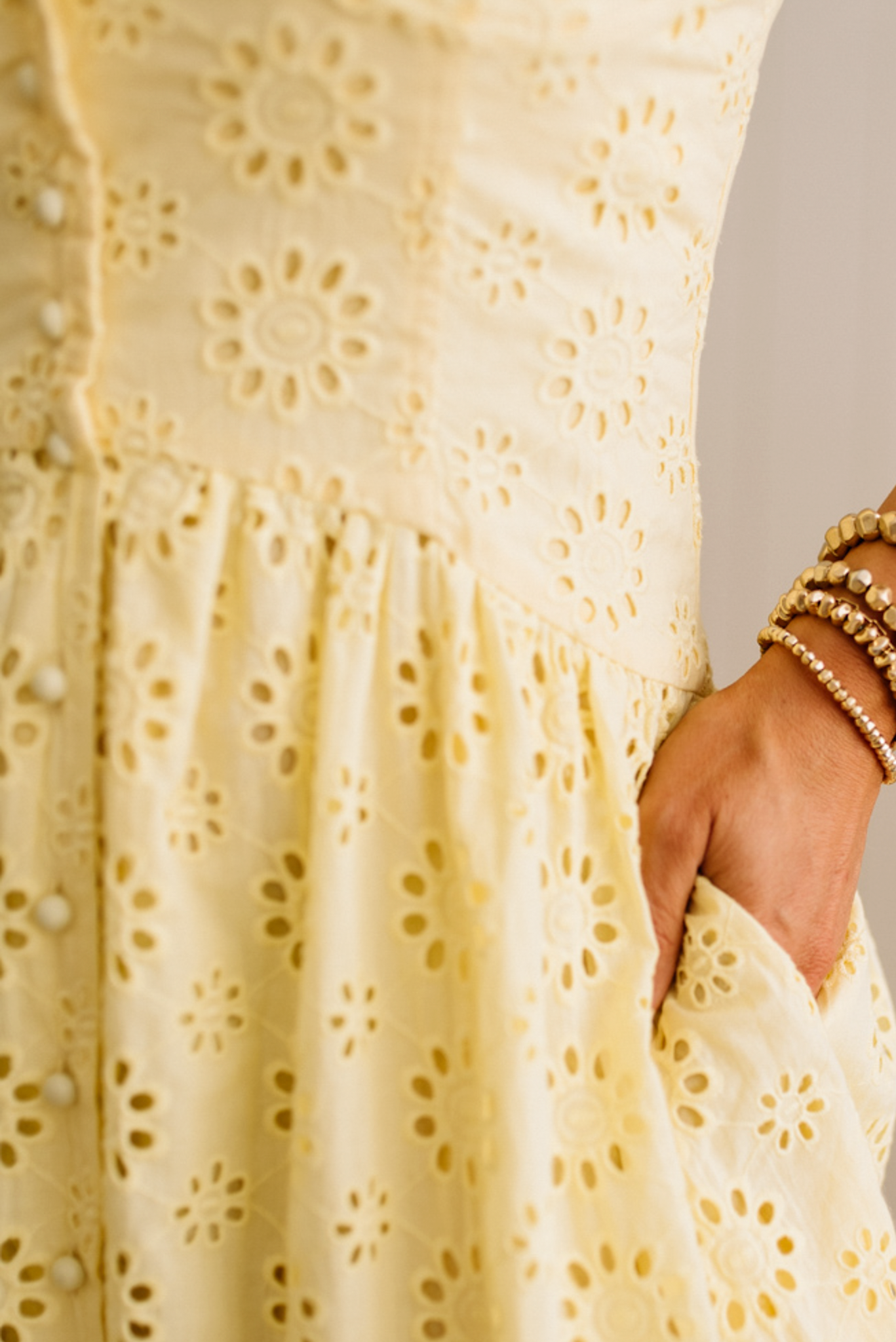 Blonde Woman wearing an eyelet lace dress with button front and spaghetti strap.