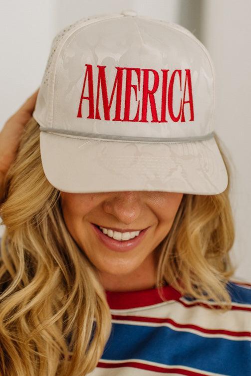 Person wearing a beige cap with 'AMERICA' in red text, smiling.