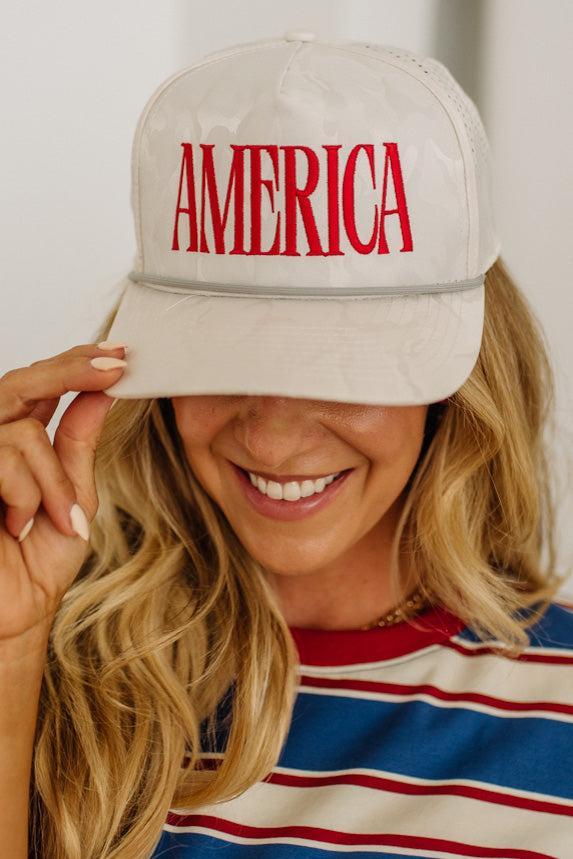 Person wearing a beige cap with 'AMERICA' in red text, smiling.