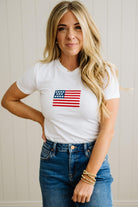 Woman wearing a white t-shirt with an American flag design and blue jeans.