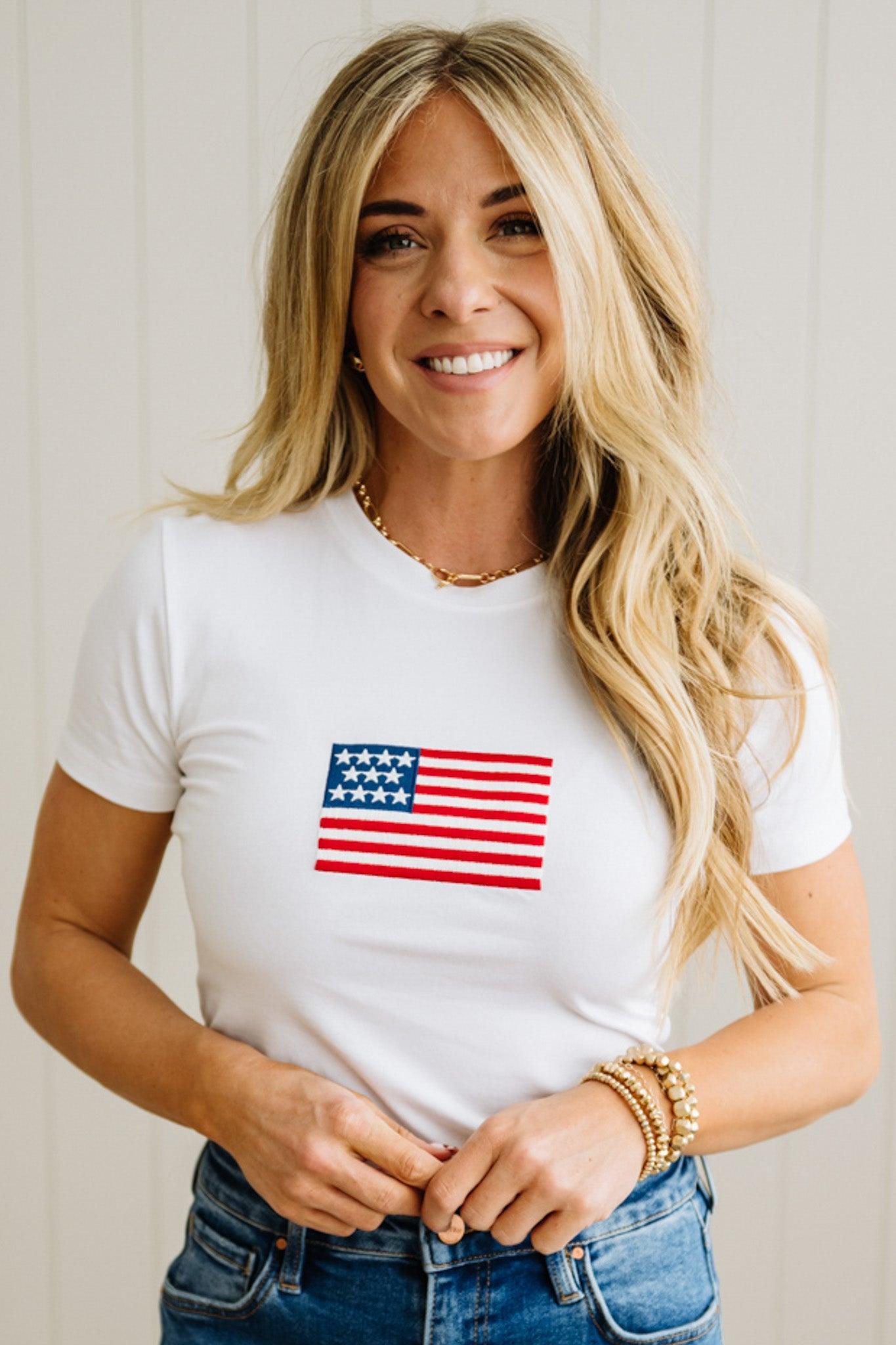 Woman wearing a white t-shirt with an American flag design against a plain background