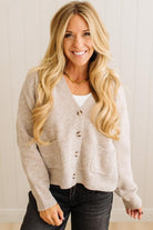 Woman wearing a beige cardigan over a white shirt with a neutral background