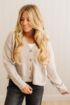 Woman wearing a beige cardigan with a neutral background