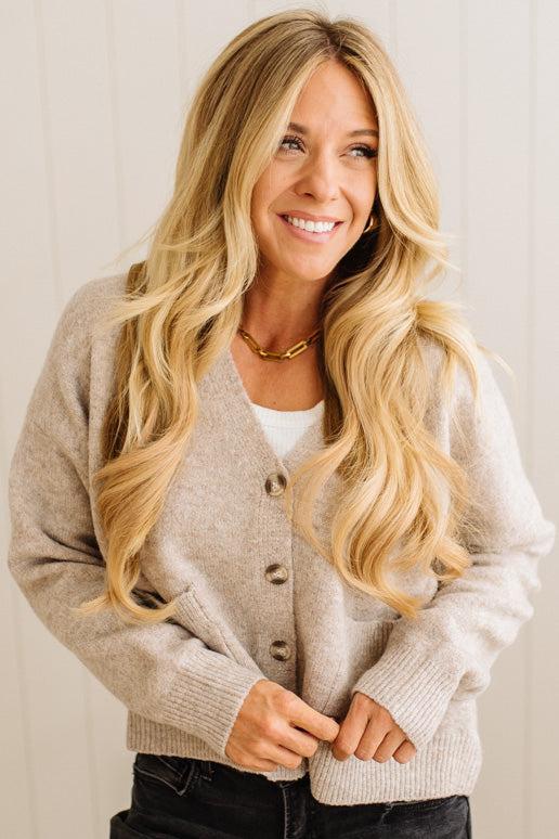 Woman wearing a beige cardigan with a plain background