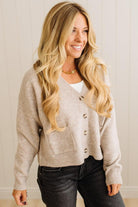 Woman wearing a beige cardigan with a neutral background