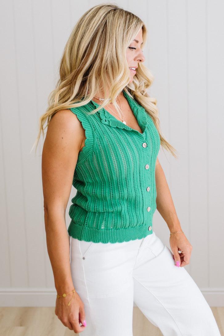 Woman wearing a green sleeveless knitted vest against a plain background