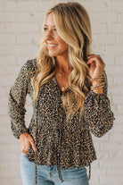 Woman wearing a leopard print top with a white brick wall background