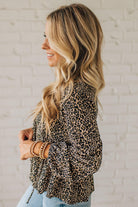 Woman wearing a leopard print top against a white brick wall