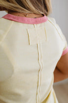Close-up of a person wearing a light-colored top with pink trim.