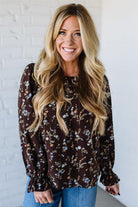 Woman wearing a floral blouse against a white brick wall