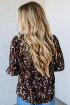 Woman wearing a brown floral blouse against a white background