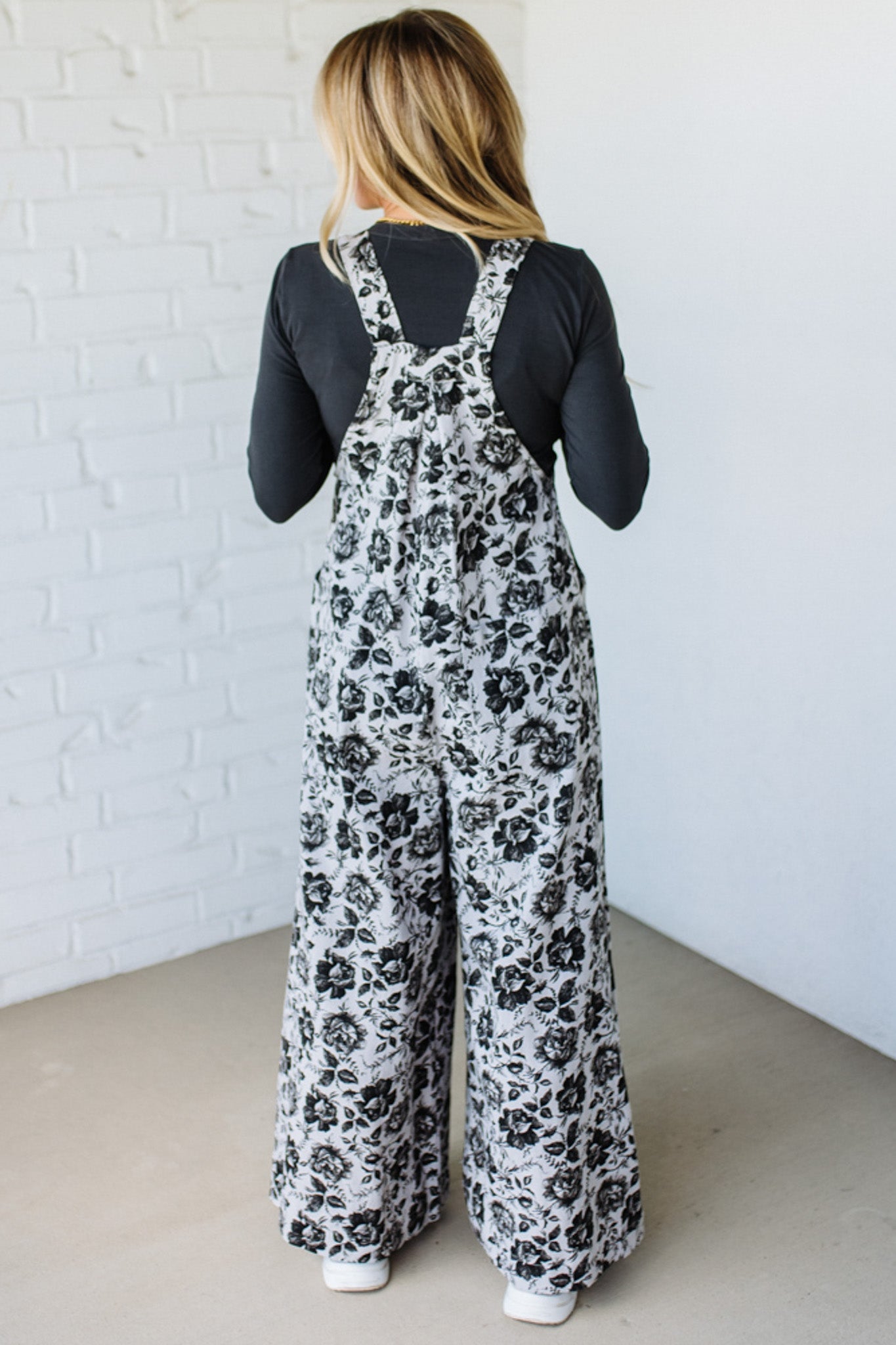 Person wearing a floral overalls with a plain background