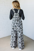 Person wearing a floral overalls with a plain background