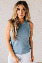 BLONDE WOMAN WEARING A ROUND NECK SLEEVELESS SLUB KNIT TOP.