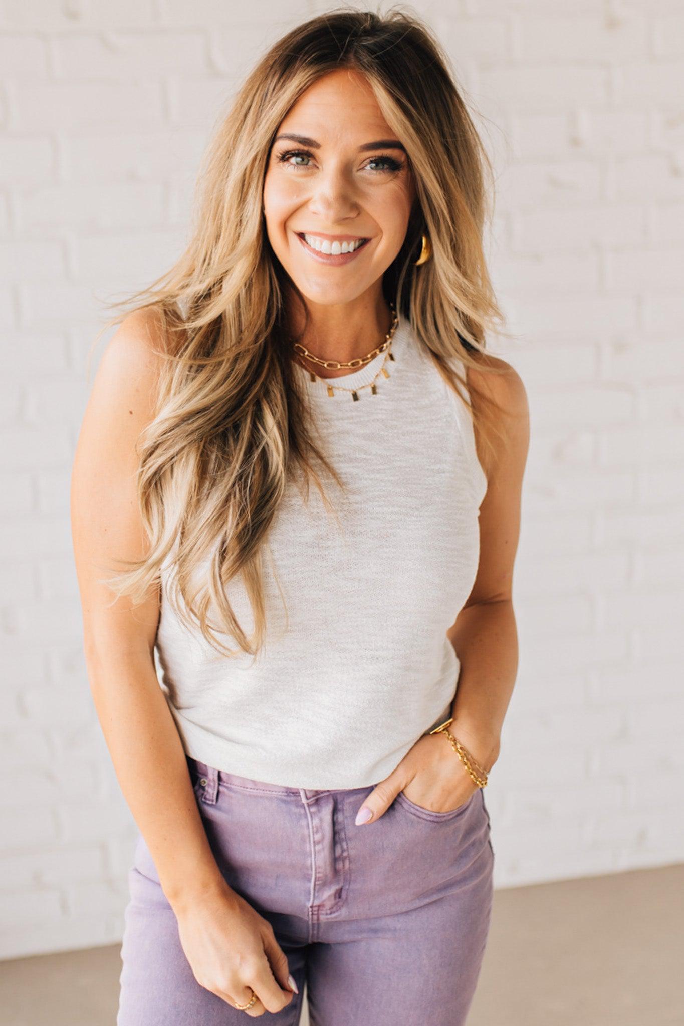 BLONDE WOMAN WEARING A ROUND NECK SLEEVELESS SLUB KNIT TOP.