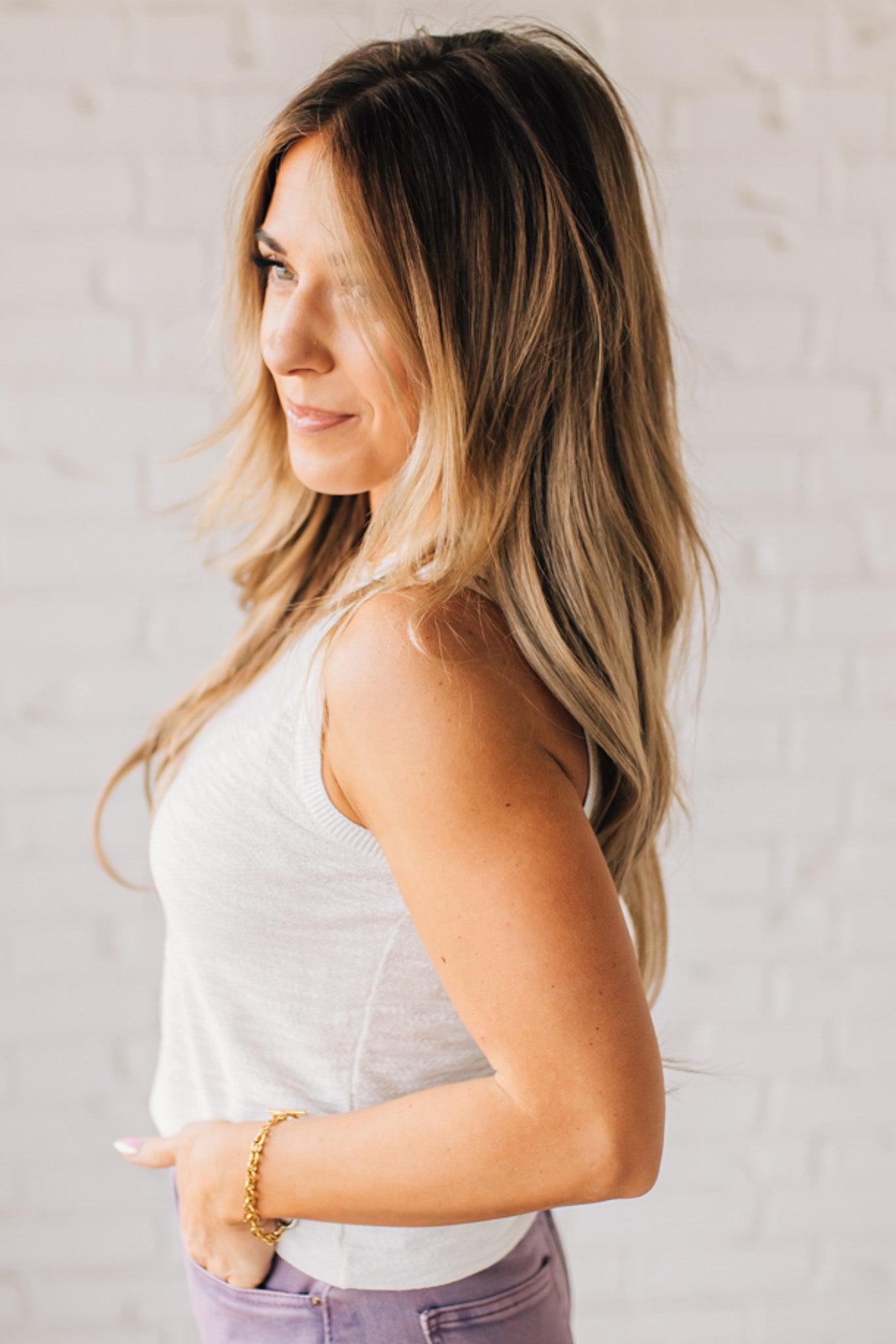 BLONDE WOMAN WEARING A ROUND NECK SLEEVELESS SLUB KNIT TOP.