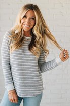 Woman wearing a striped sweater against a white brick wall