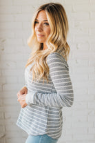 Woman wearing a striped sweater against a white brick wall