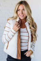 Woman wearing a white and brown striped jacket with a plain background