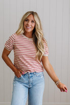 Woman wearing a striped shirt and jeans against a light background