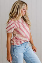 Woman wearing a red and white striped shirt and light blue jeans against a neutral background