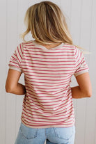 Person wearing a red and white striped shirt with blue jeans against a light wooden panel background